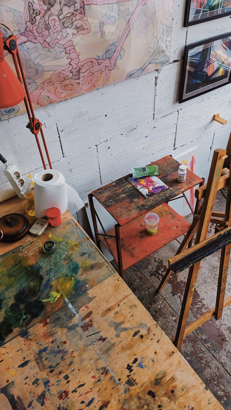 Künstlerwerkstatt mit Malutensilien und abstrakter Kunst an den Wänden.